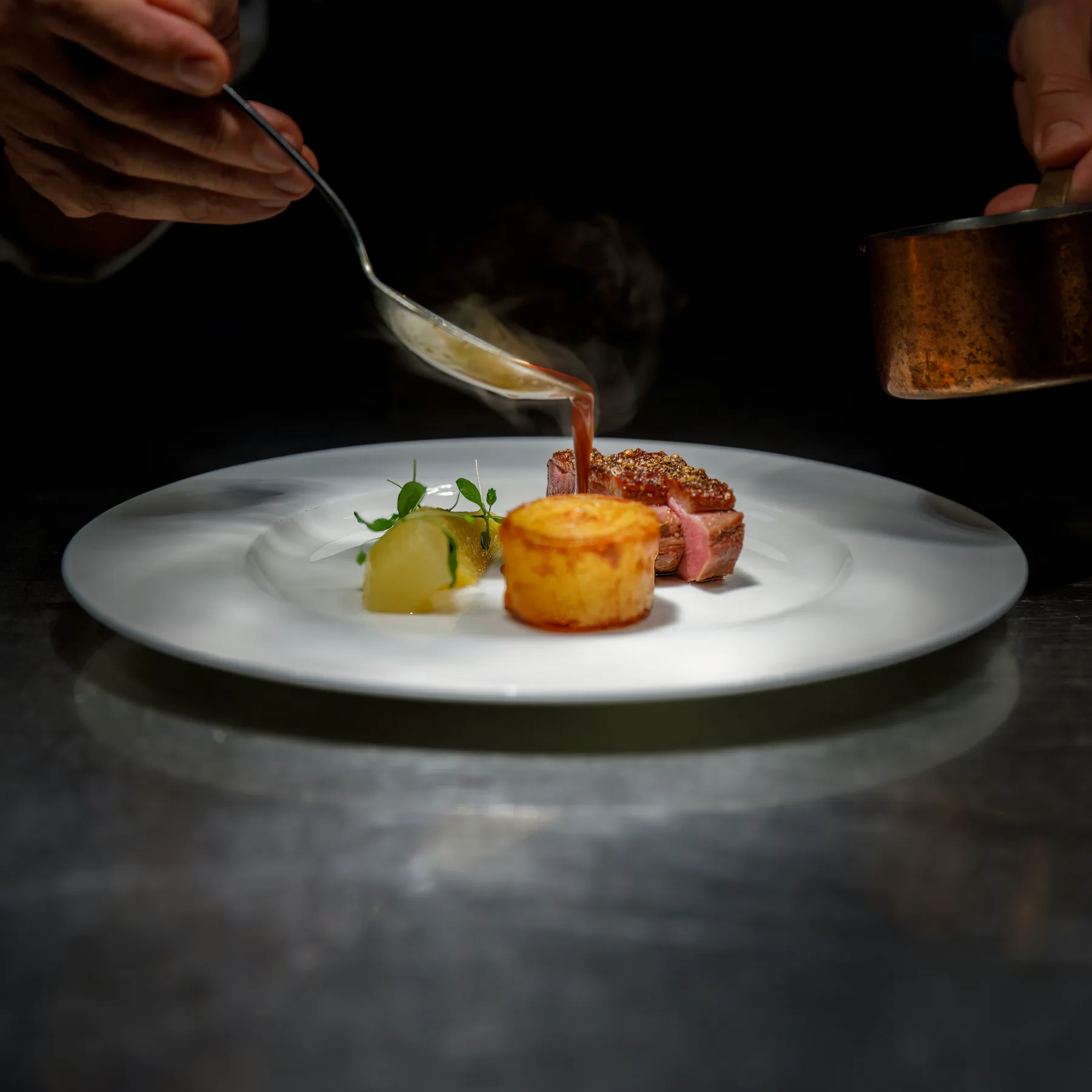 Sauce finished over a meat course at the pass